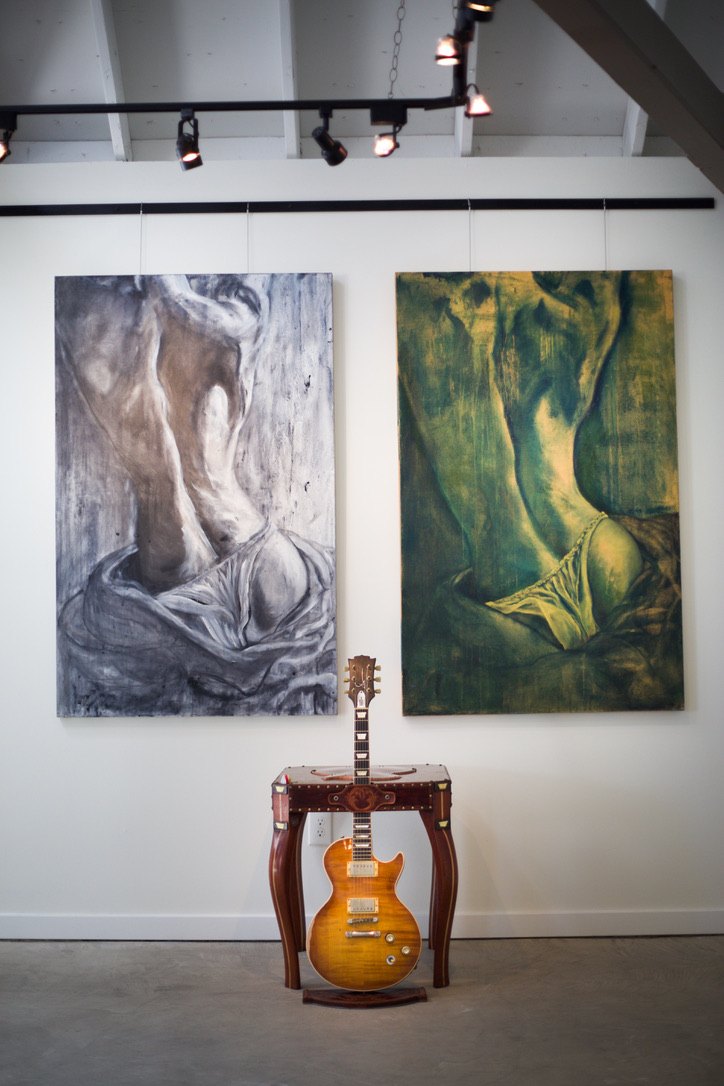 Two large figurative paintings, one in cool grey and one in warm green, hung side by side in a gallery space.